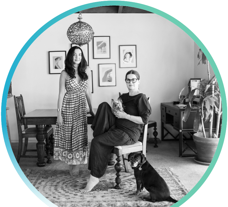 Two women and their pet dogs in their dining room.