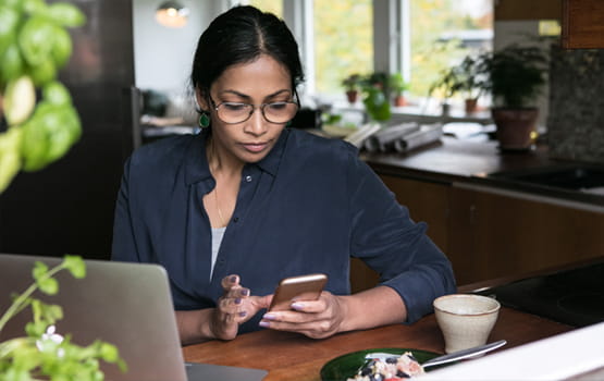 Woman at a restaurant with a laptop and cell phone