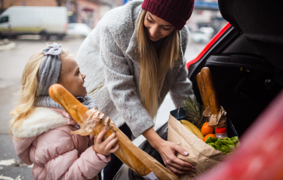 Mother and child putting groceries into the trunk of a car