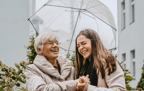 Two smiling women under an umbrella