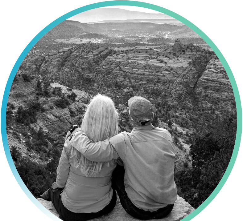 A couple sitting on top of a cliff