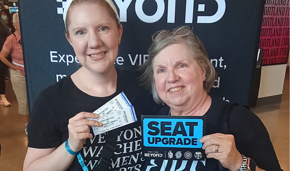 Two women showing their seat upgrade tickets