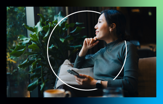 Woman in coffee shop holding a mobile phone. Plants in the background.