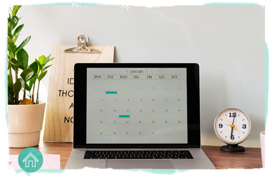 desk showing a clock and a laptop computer with a calendar app open