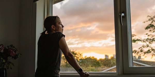 Woman looking out a window at distant fire.