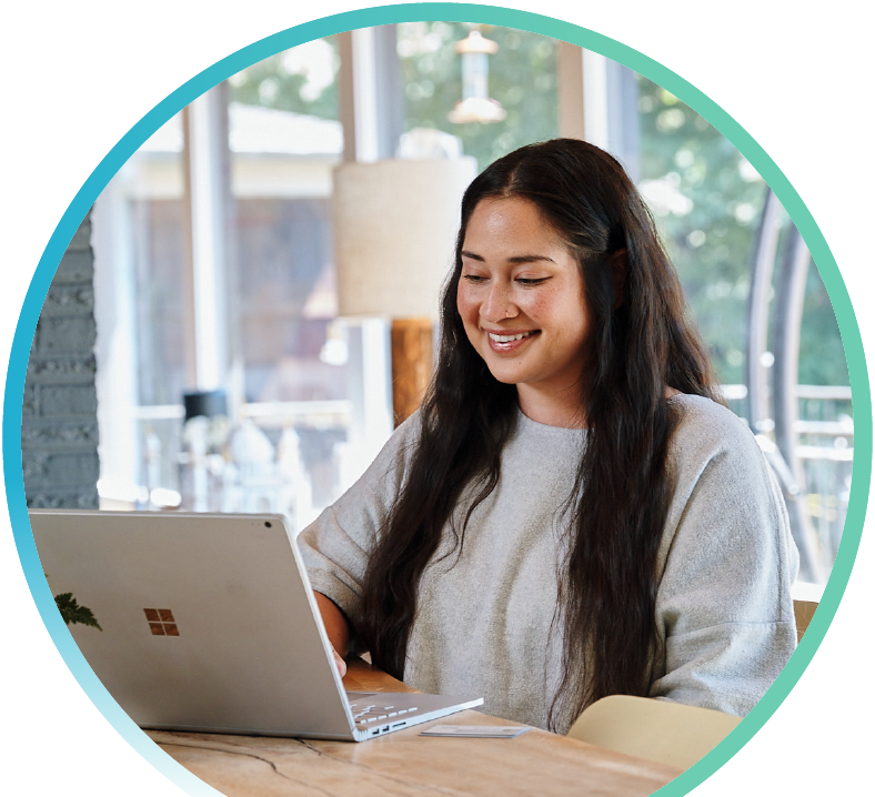 Image of a woman sitting at a table working on a laptop.