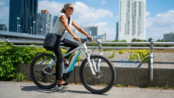 Woman in white shirt riding a bicycle on a city bike path