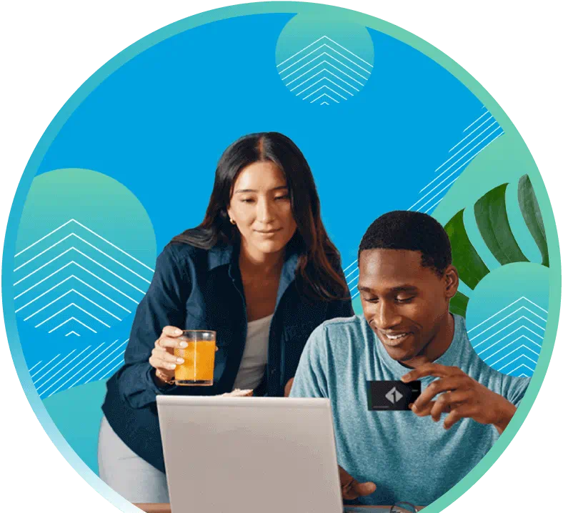Woman holding a glass of juice and man holding a First Tech card looking at a laptop computer