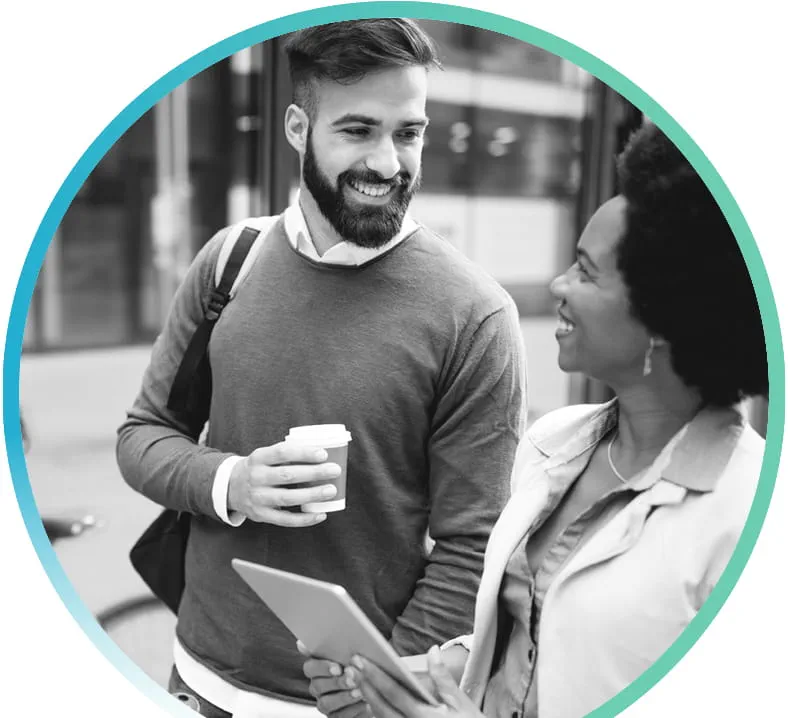 Two people walking outside together. One person is holding drink in one hand, other person is holding tablet