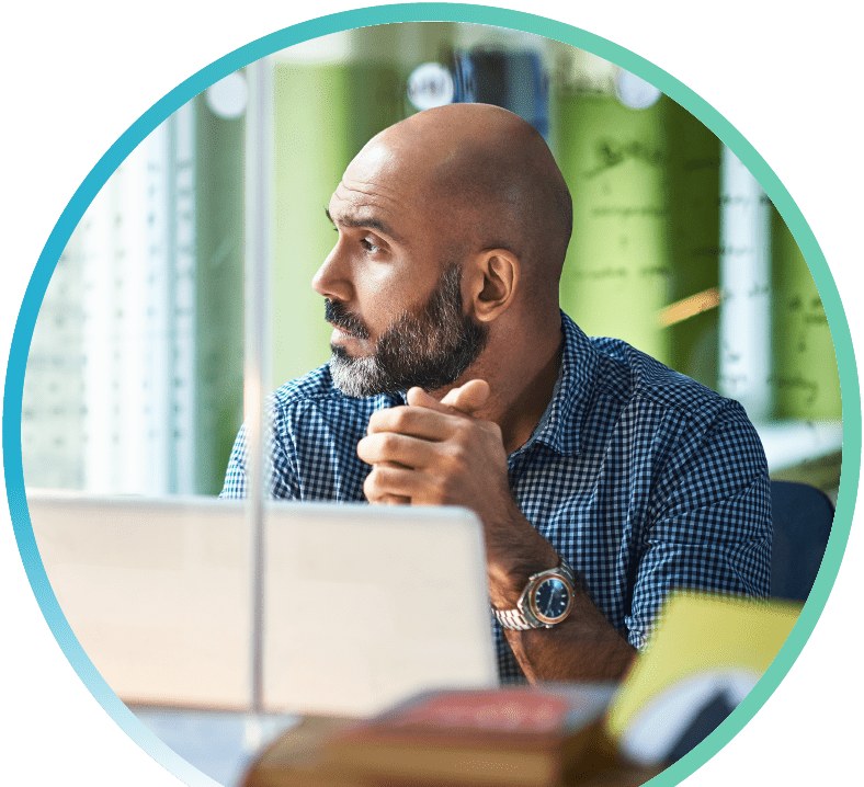 Image shows a man looking out a window with an open laptop in front of them.