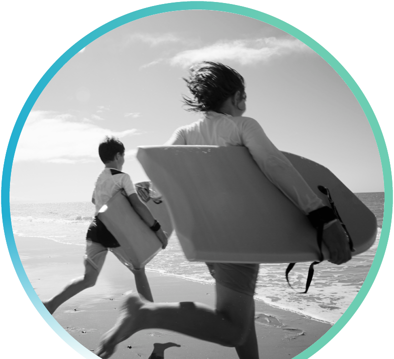 Two people at the beach carrying surfboards and running towards the ocean