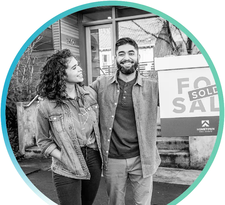Couple in front of FOR SALE sign with the word SOLD placed across the sign