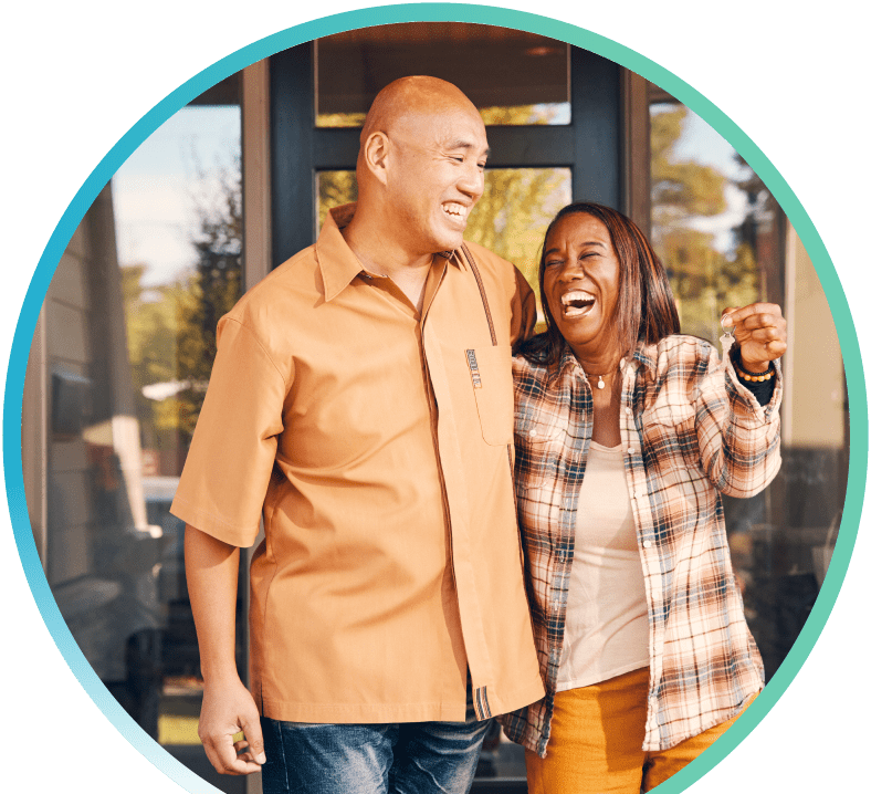 A couple standing in a doorway celebrating with one another, while the wife holds up keys.