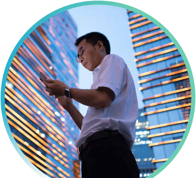 Man surrounded by high-rise building looking at his mobile phone.