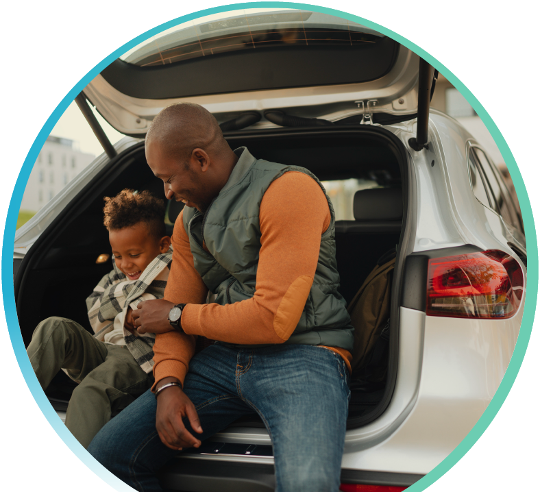 Man and child seated in the back of a car with a hatch back