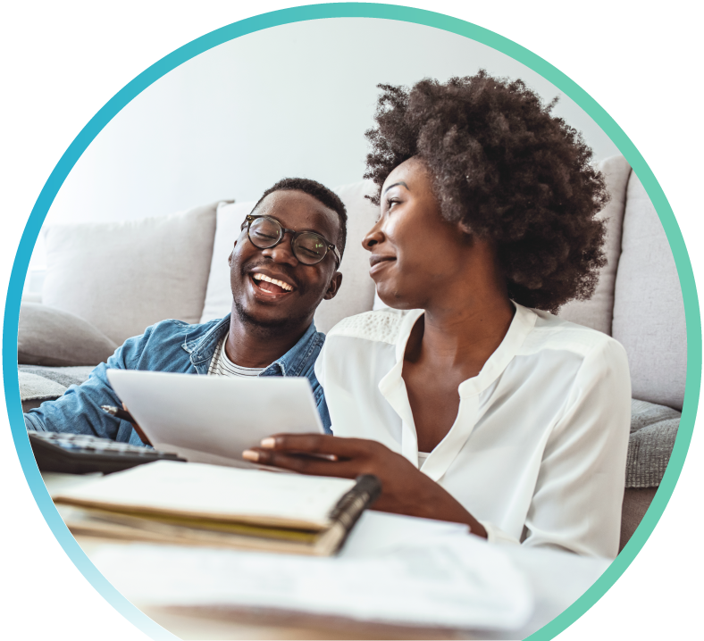 Black couple smiling and looking at paperwork and a computer