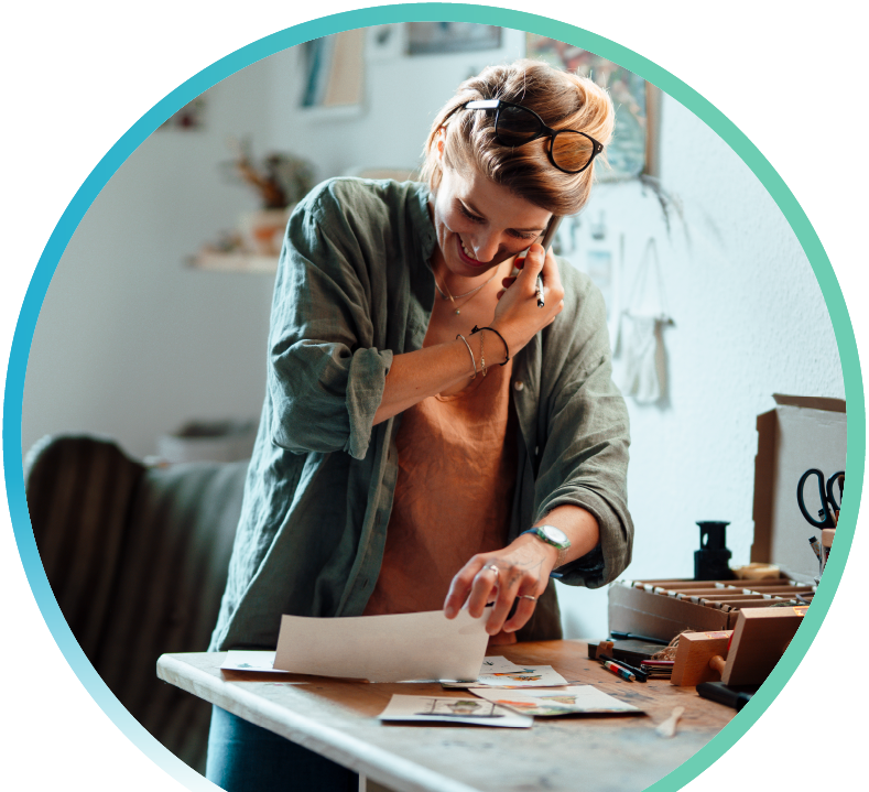 woman holding phone and looking at craft items on a desk