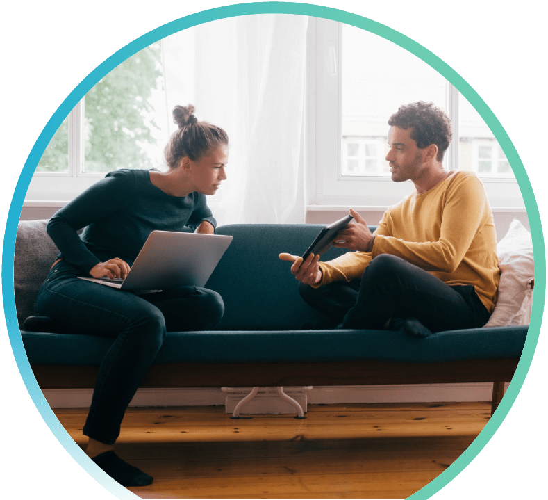Woman with a laptop computer and man with a tablet sitting on a sofa