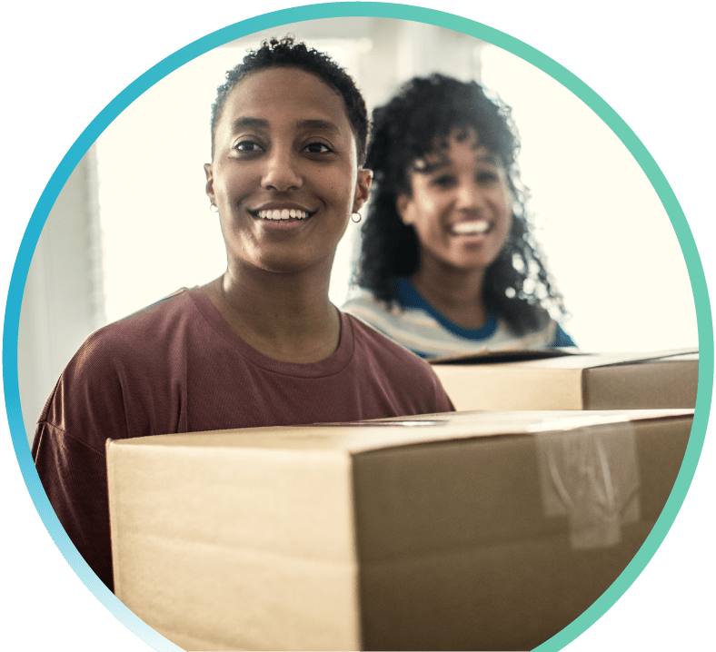 Two women holding moving boxes.