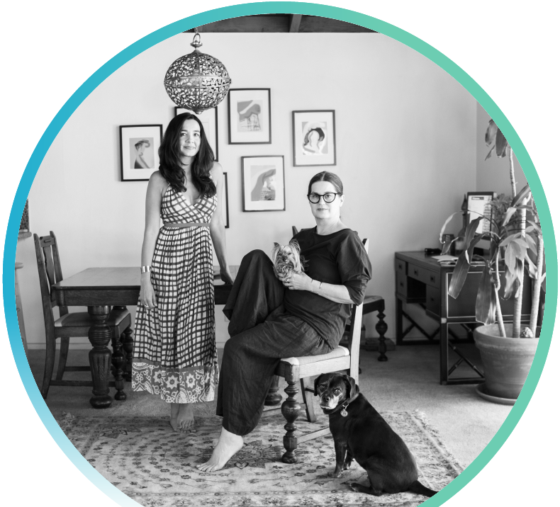 Two women and their pet dogs in their dining room.