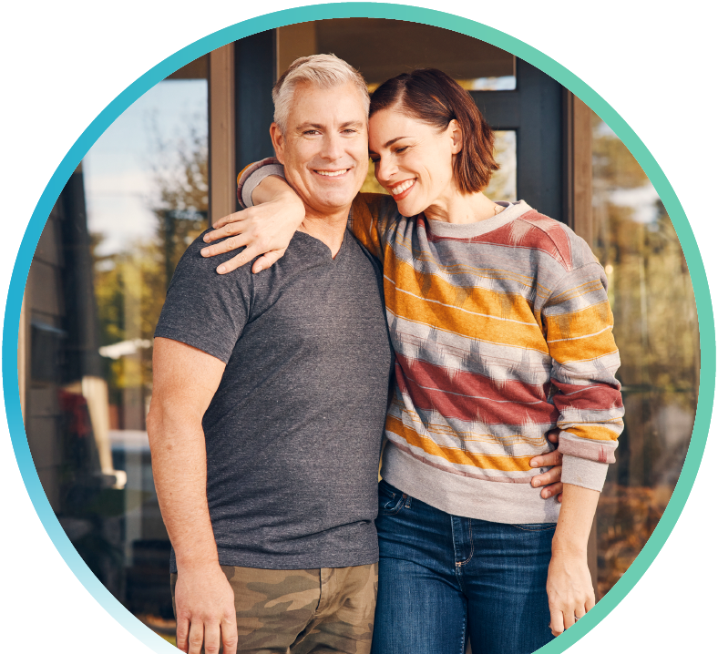 Two people hugging and smiling in front of a building.