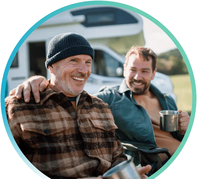 Two men sitting outside in front of an RV.