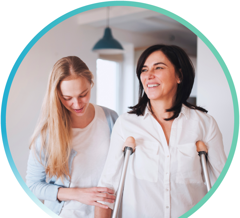 Two women are shown in the image. One woman is on crutches, while also being assisted by the other woman.