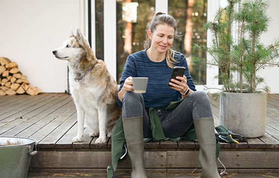 Woman sitting on a porch with a dog looking at her phone