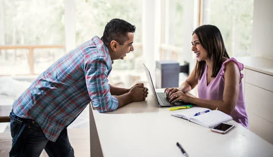 Couple using computer at kitchen counter