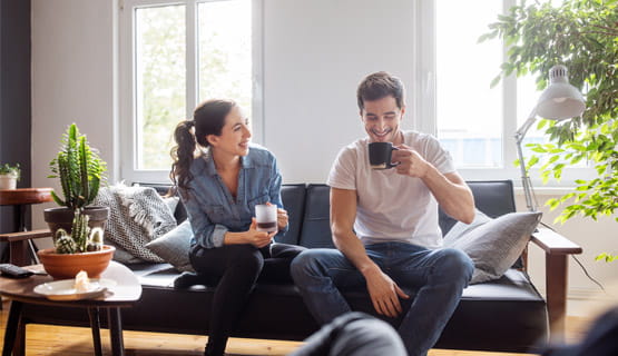 Couple sitting on the couch together and both drinking coffee