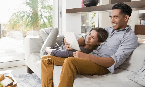 Couple on a couch looking at a laptop.