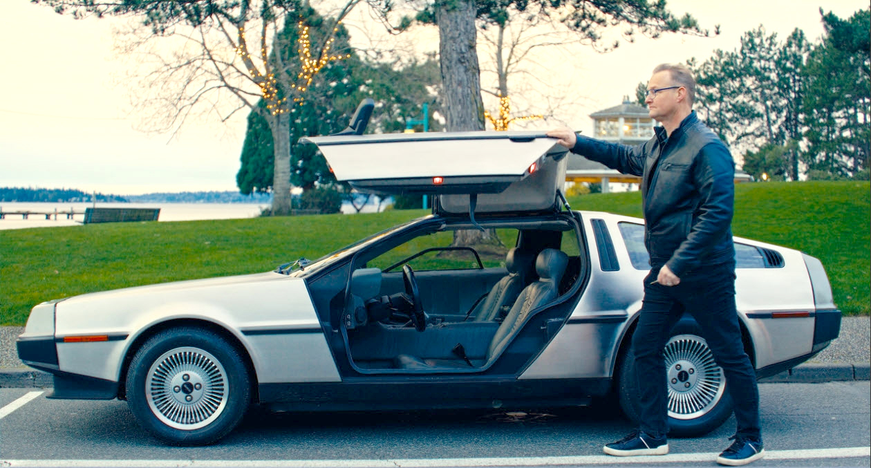 Man with gull-wing sports car.